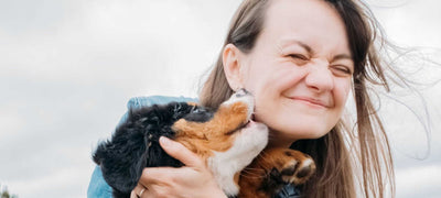 Woman holding a dog outdoors with a blurred background